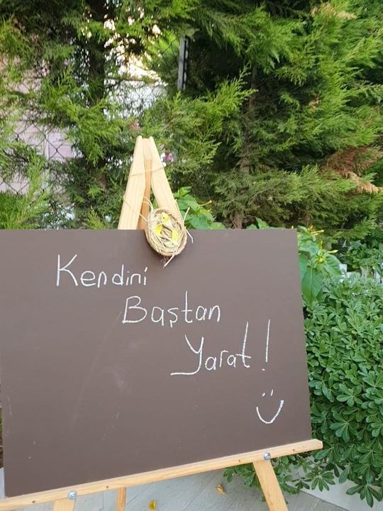 Bahçede “Kendini Baştan Yarat!” yazılı kara tahta