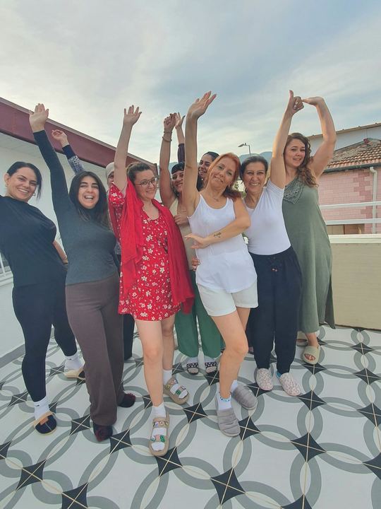 Terasta kollarını havaya kaldırmış neşeli grup